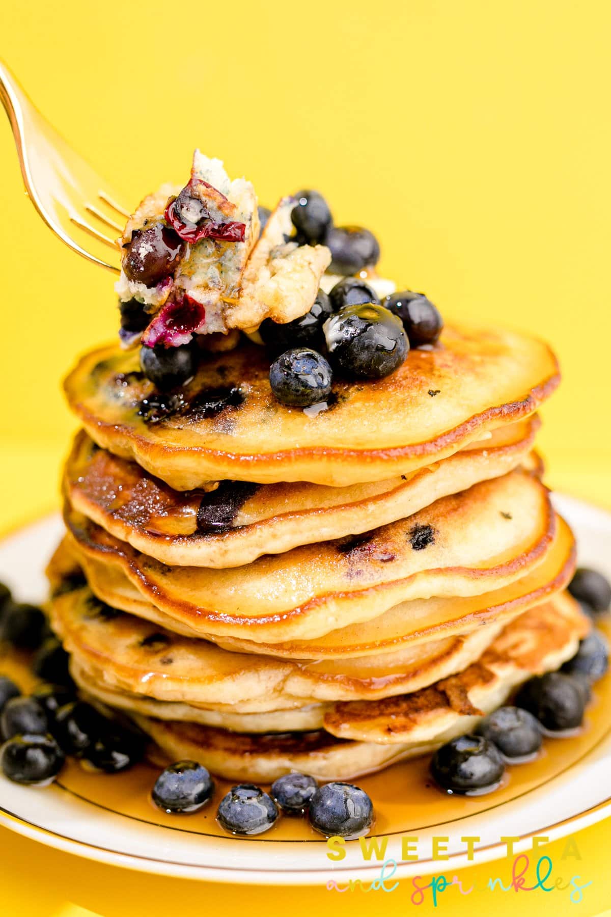 Stacked Fluffy Blueberry Pancakes with fork holding bites of pancakes.
