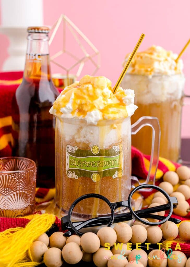 Homemade Butterbeer in glass with props around cup.