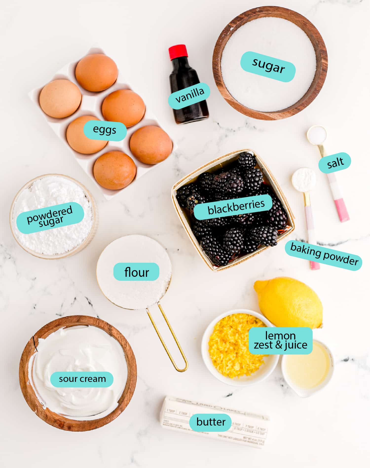 Labeled ingredients used to make blackberry lemon bread laid out on a marble counter top.