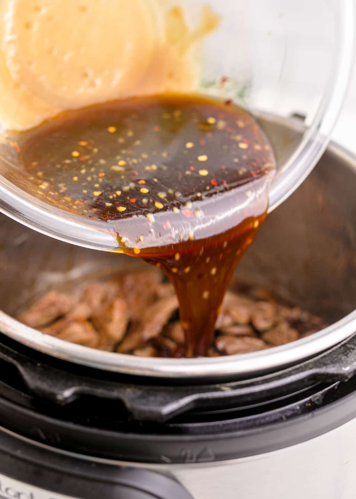 Seasoned sauce being poured over the cooked meat and with broth.