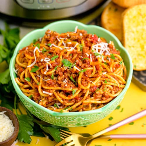Spaghetti sauce and noodles in a green bowl in front of an Instant Pot.