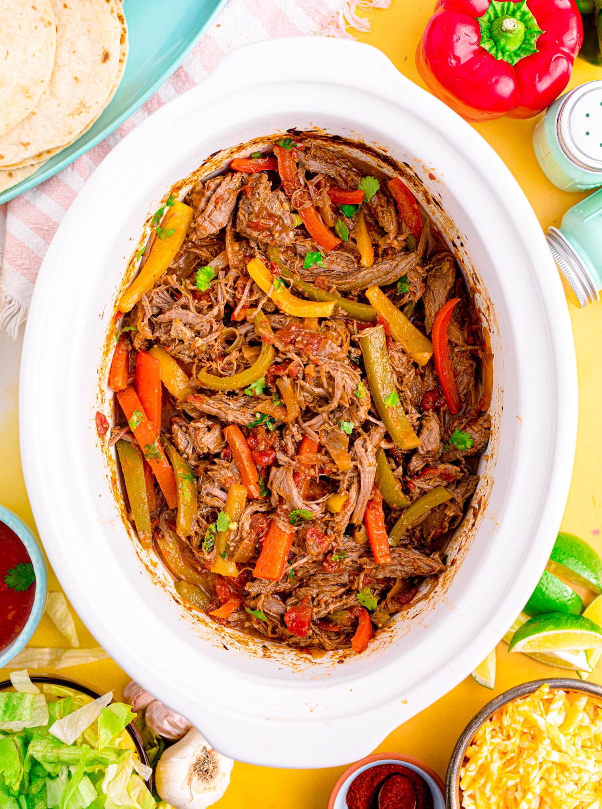 Shredded steak fajitas in a slow cooker with bell peppers.