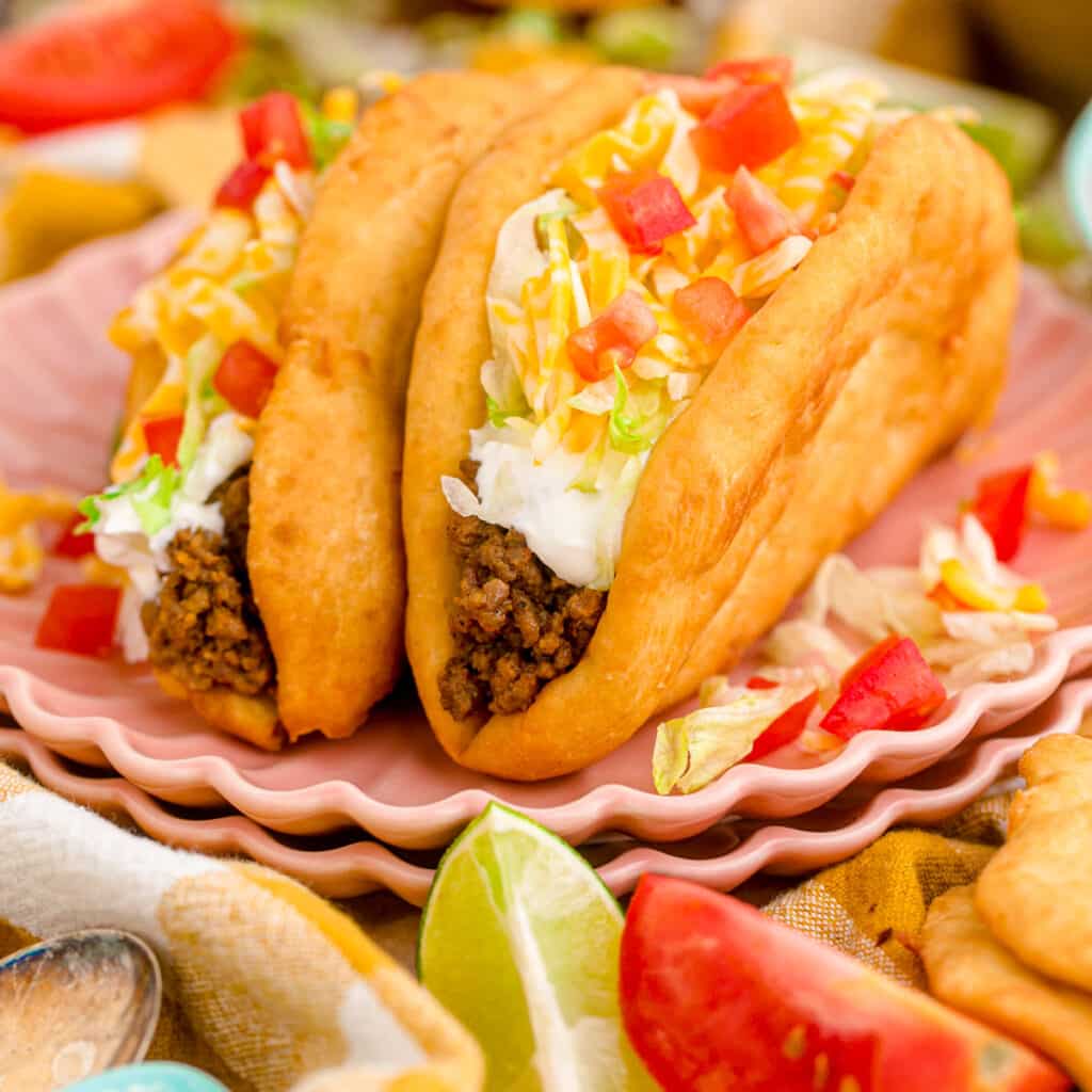 Taco Bell copycat chalupas on a plate filled with beef, sour cream, cheese and tomatoes.