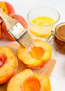 Melted butter being brushed onto peaches.