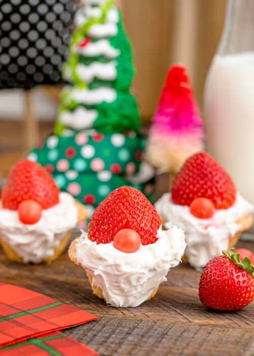 Mini Christmas gnome cookies on a wooden table with milk and Christmas trees.