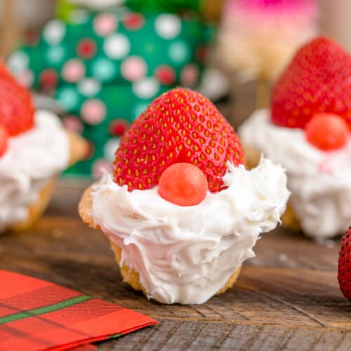 A Christmas gnome cookie cup with a frosting beard, strawberry hat and skittle nose.