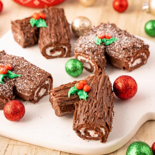Christmas Yule logs made out of little Debbie Swiss rolls sitting on a platter decorated for Christmas.