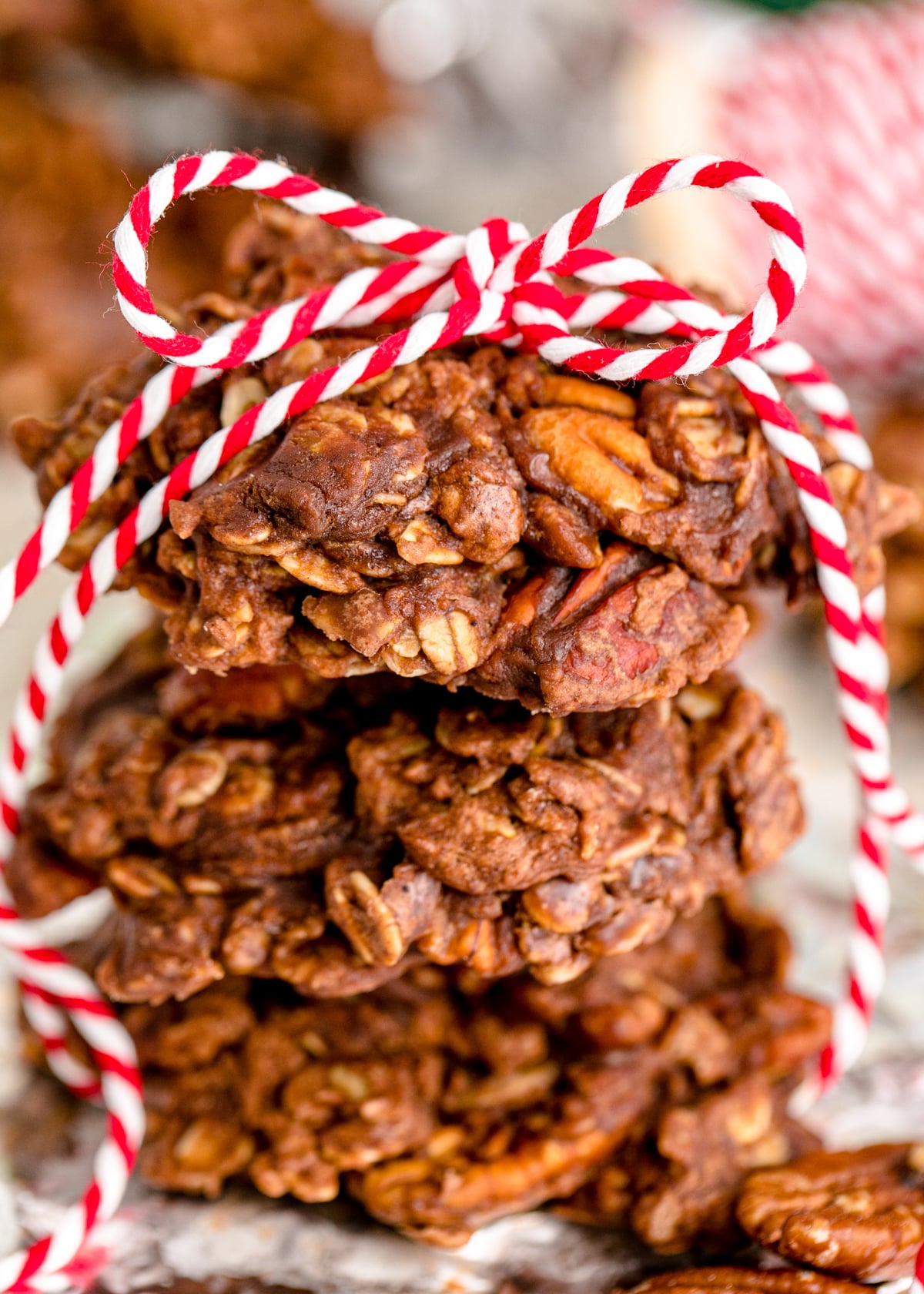 Three no bake chocolate peanut butter cookies with pecans stacked on top of each other and tied with a ribbon.