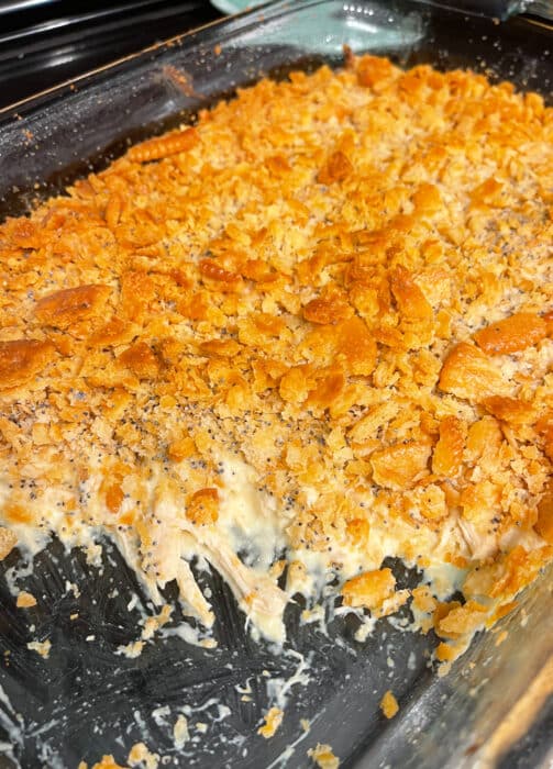 Poppy seed chicken casserole topped with buttered Ritz crackers in a glass 9X13 baking dish.