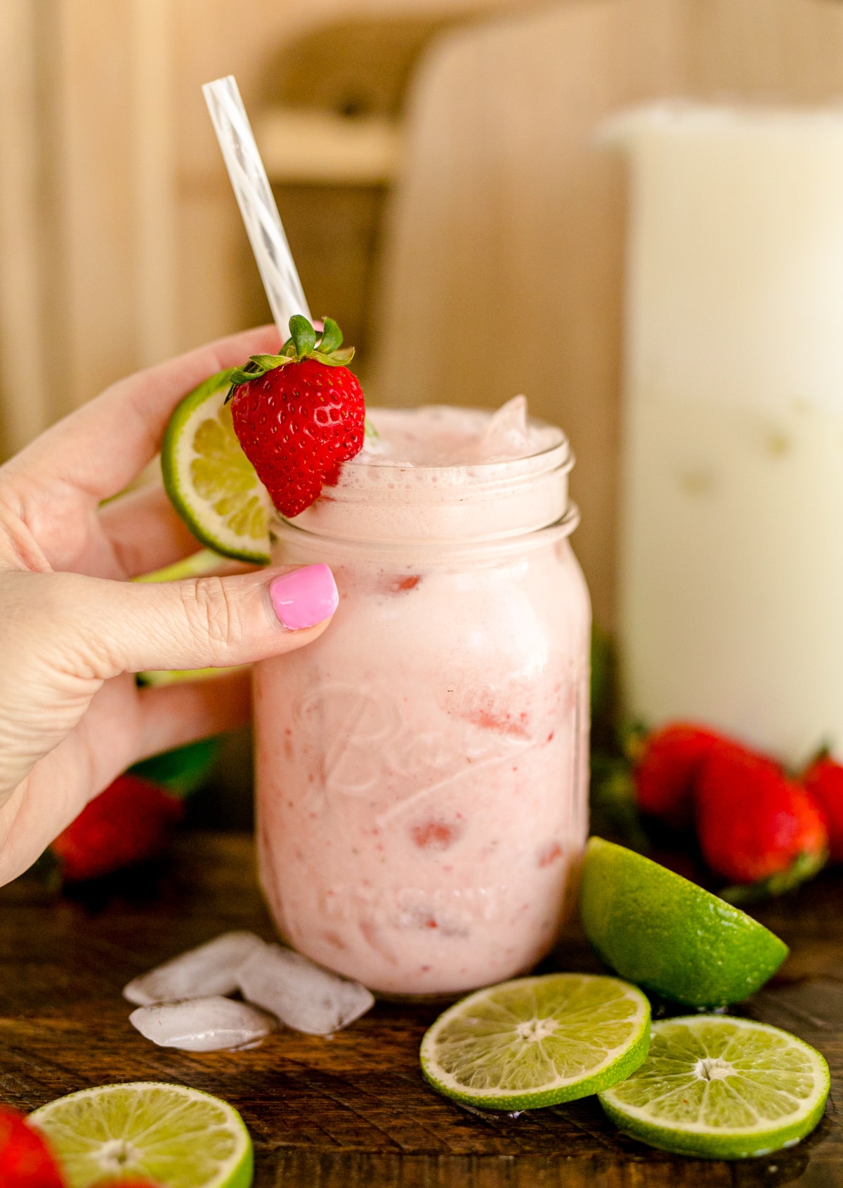 Creamy strawberry limeade in a mason jar with a straw.