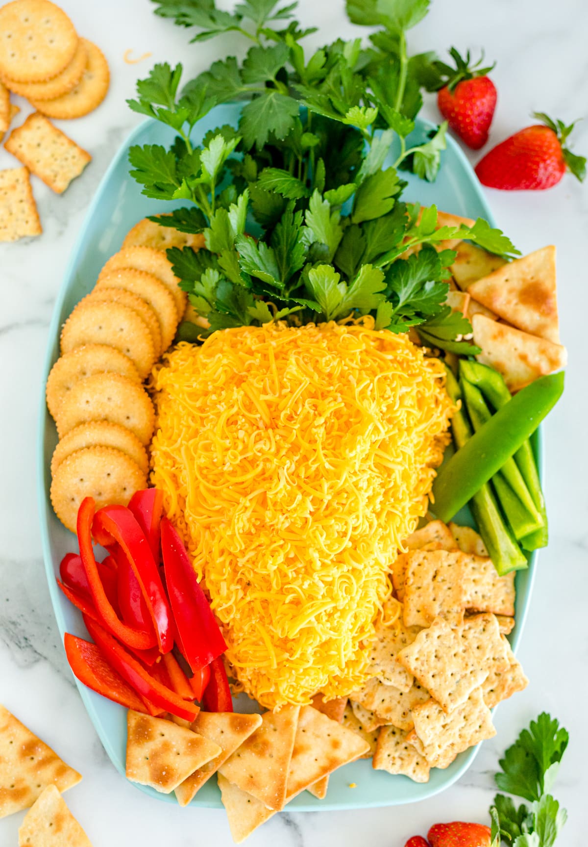 An Easter carrot cheese ball on a platter with crackers and veggies.