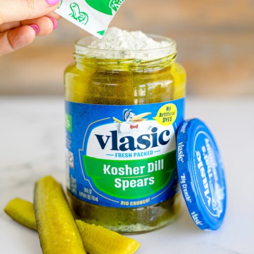 Ranch seasonings being poured into a kosher dill spears pickle jar.