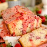 A loaf of freshly baked strawberry bread glazed with strawberry icing.
