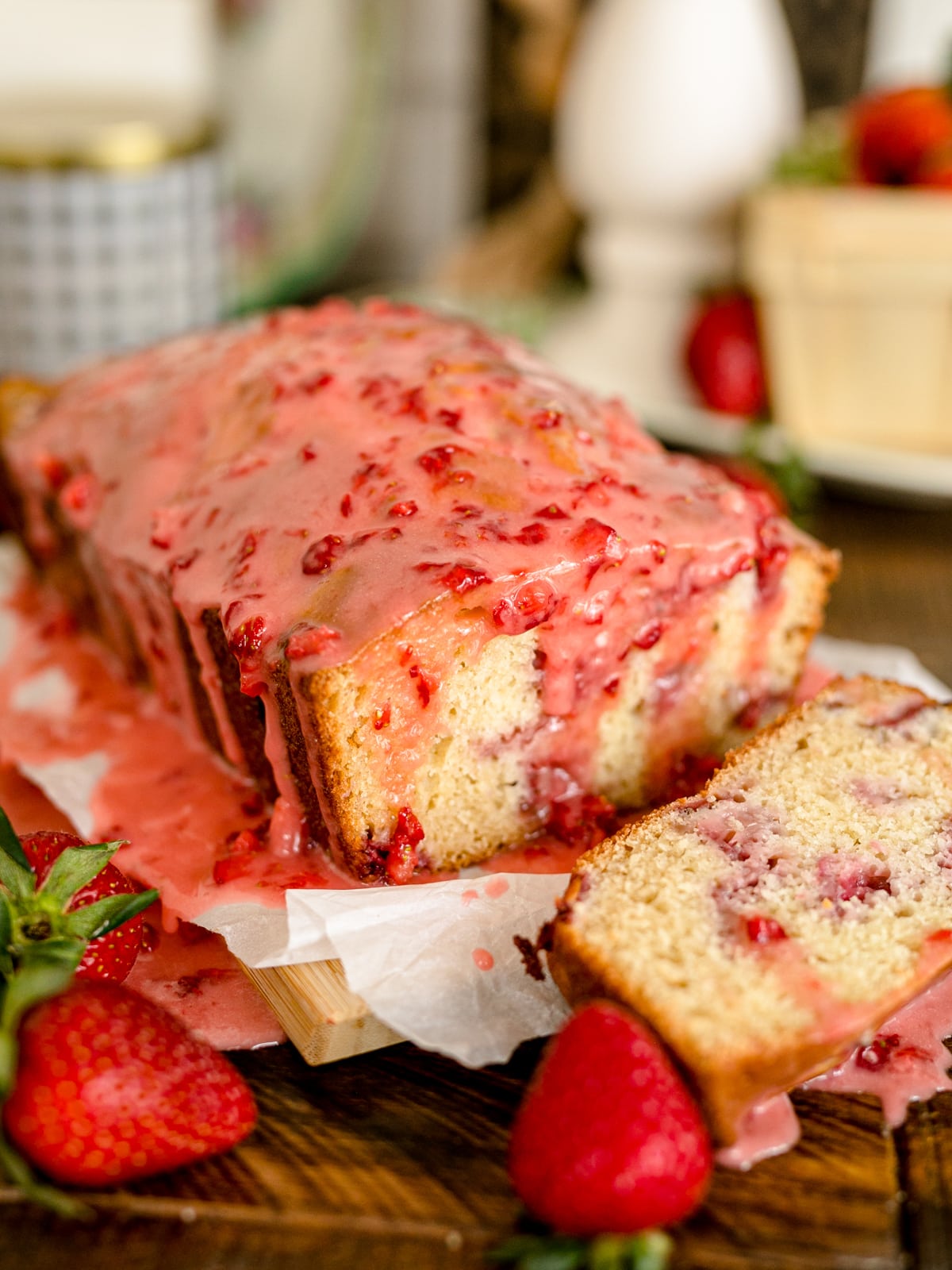A loaf of strawberry bread with strawberry icing poured over top of it.