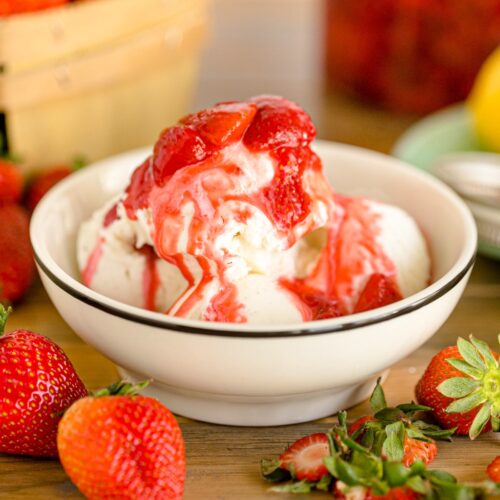 Strawberry sauce drizzled over top of a bowl of vanilla ice cream.
