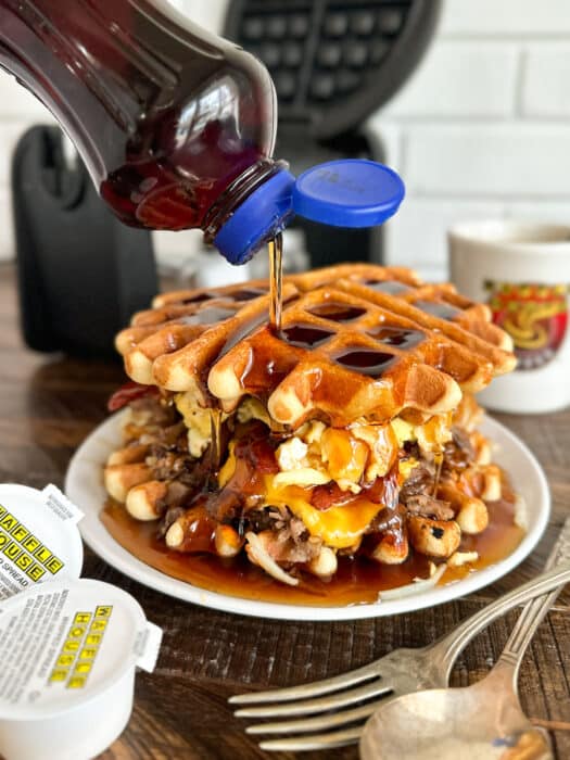 Syrup being poured over the waffle house sandwich.
