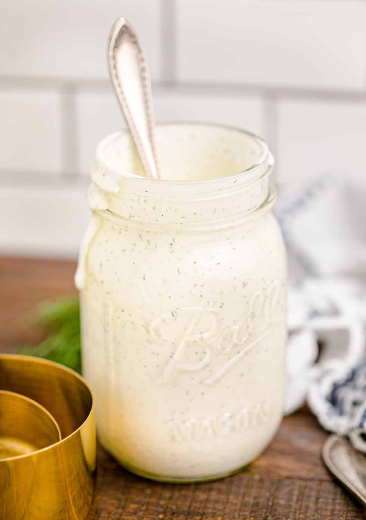 Restaurant style ranch dressing in a mason jar with a spoon.