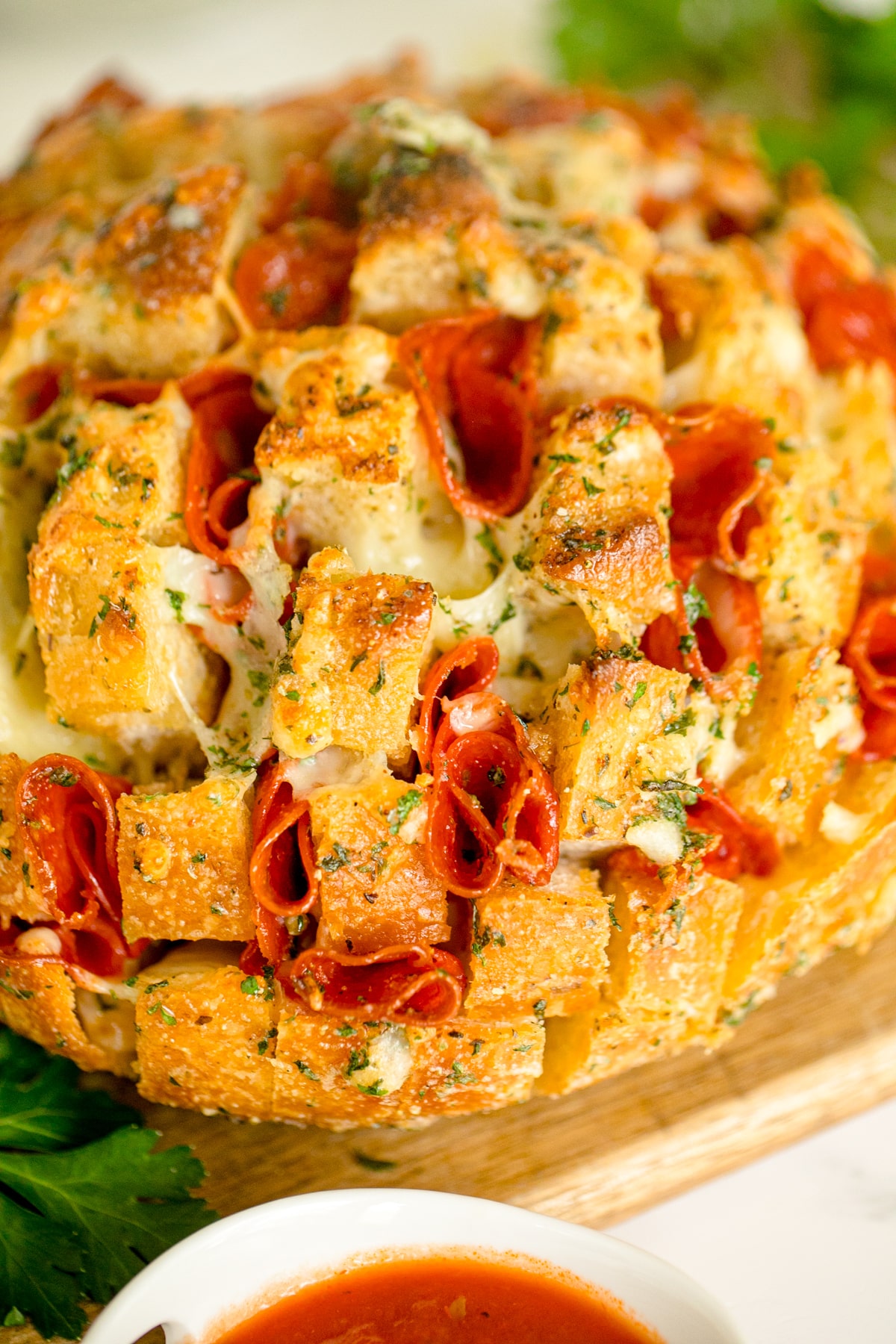 Pull apart pizza bread on a wooden cutting board next to marinara sauce.